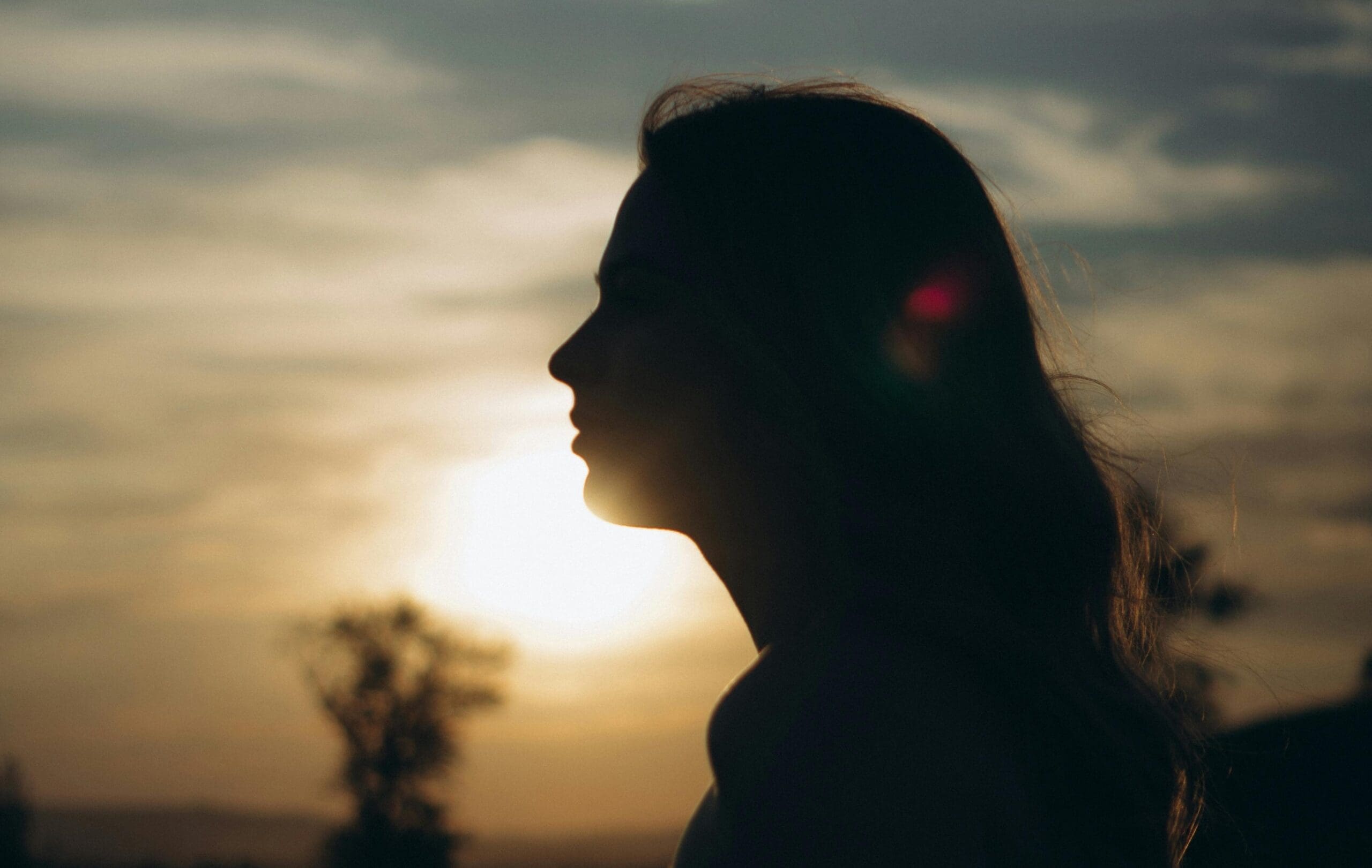 woman silhouette with a sunset landscape background