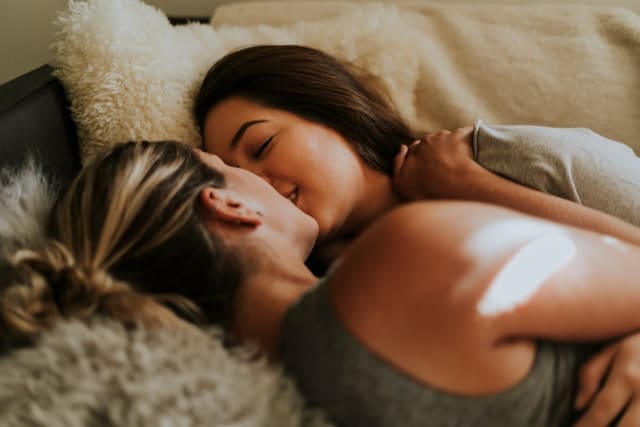 two woman embracing in bed
