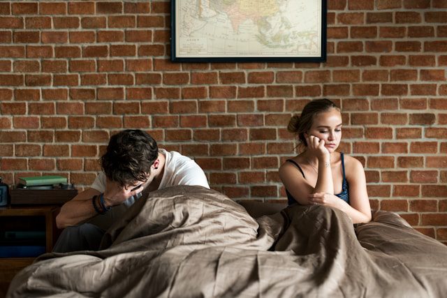 limerence for an ex - a man crying in his hands and woman turns away from him in bed